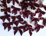 30 maroon satin ribbon bows with a centre wire for attachment. 7cm x 6cm . Clearance sale, less than 9p each. Ribbonmoon UK craft & sewing online.