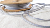 Spool of gray cord on a white fabric background