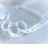 Loops of 15mm white rustic taffeta ribbon showing metallic festive lettering and star motifs.