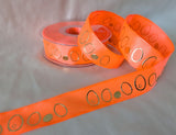 Close‑up of neon orange wired taffeta ribbon showing the raised metallic gold‑embossed oval design and crisp taffeta texture.