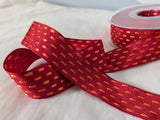 25mm red stitched ribbon with orange dash pattern, displayed in decorative loops beside the spool for product showcasing
